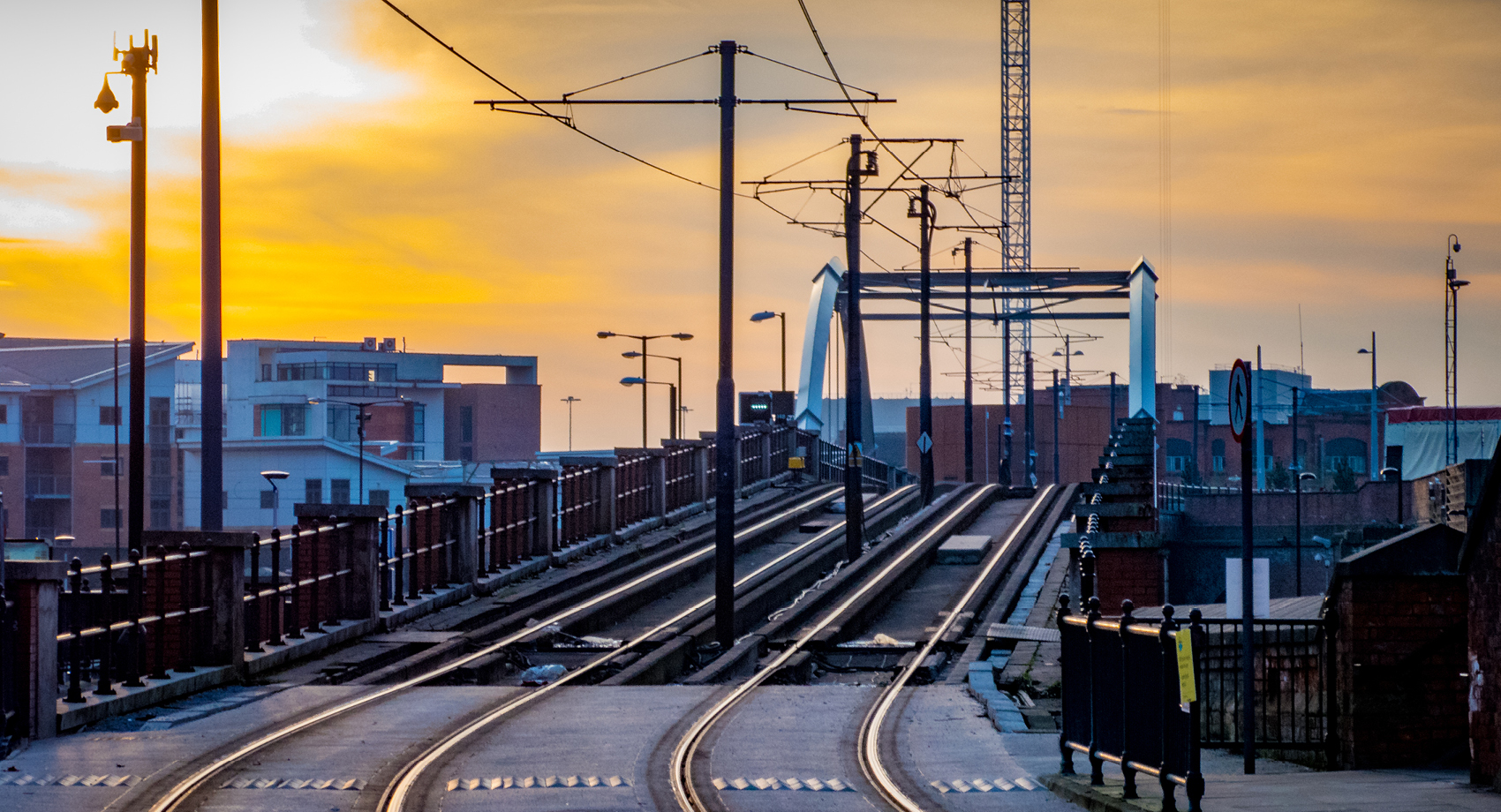 Tram and tramlines in central Manchester, UK, with setting sun and clouds.