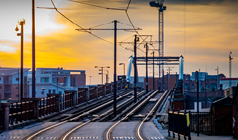 Tram and tramlines in central Manchester, UK, with setting sun and clouds.